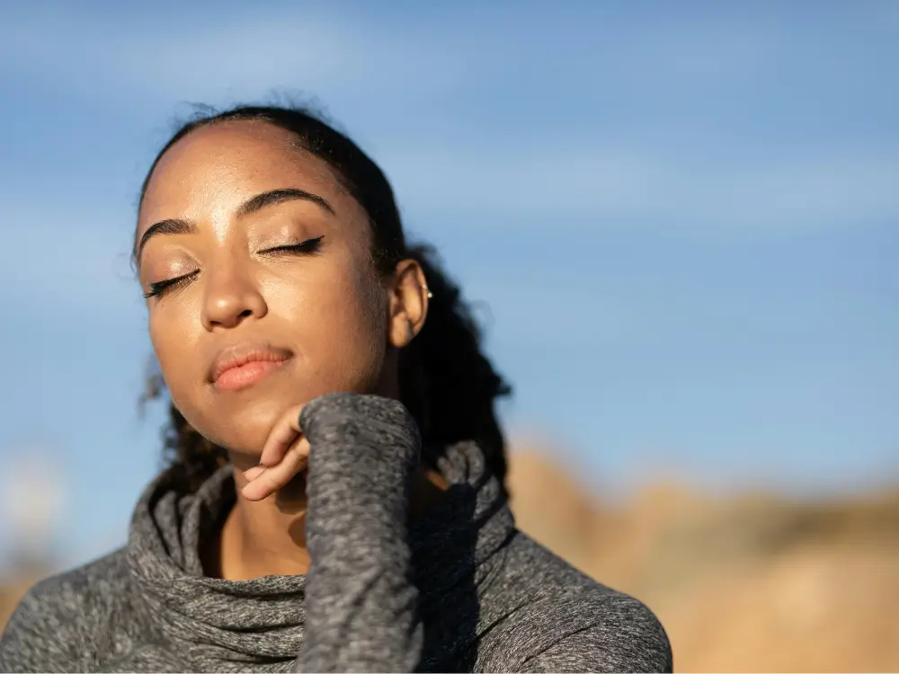 "Mulher 40+ sorrindo ao ar livre, representando nova fase da vida com fé".