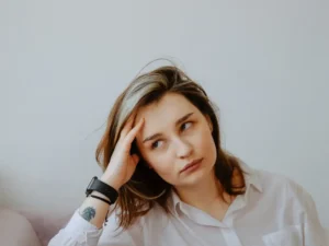 Mulher de 40+ com expressão pensativa ou curiosa, em ambiente tranquilo (casa ou natureza), com luz suave. O olhar pode estar voltado para o lado, como quem reflete.