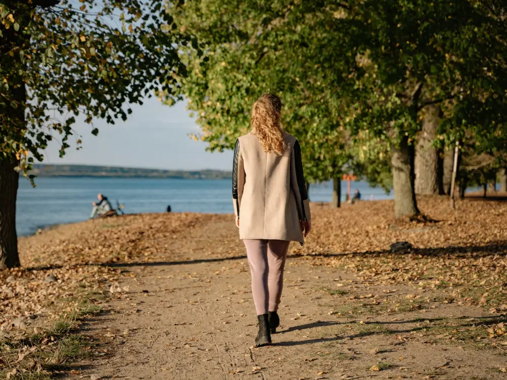 “Mulher 40+ caminhando em meio à natureza, representando equilíbrio entre corpo e mente.”
