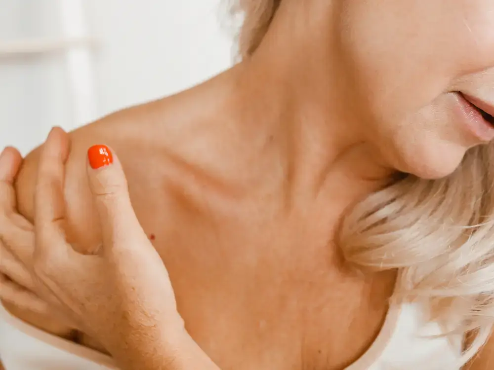 Mulher com dor no ombro, ilustrando a Síndrome do Ombro Congelado na menopausa