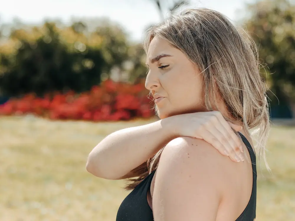 Mulher com dificuldade de movimento no ombro, ilustrando a Síndrome do Ombro Congelado na menopausa